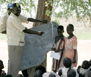 Bol Deng teaches the children with a slab of chalkboard
