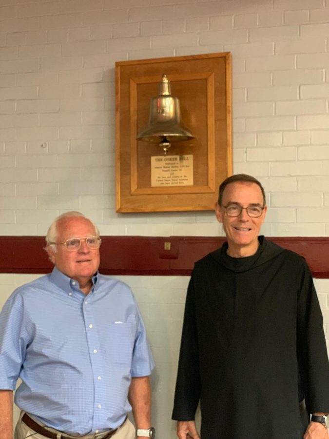 Fr. Edwin and Mr. Coker pose by the Coker Bell named after the war hero.